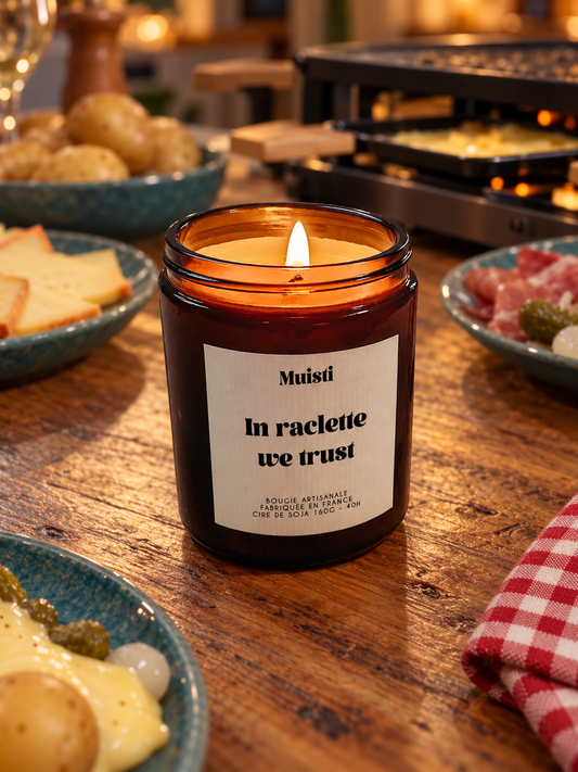 Bougie Muisti « In raclette we trust » allumée sur une table de raclette, en soirée.