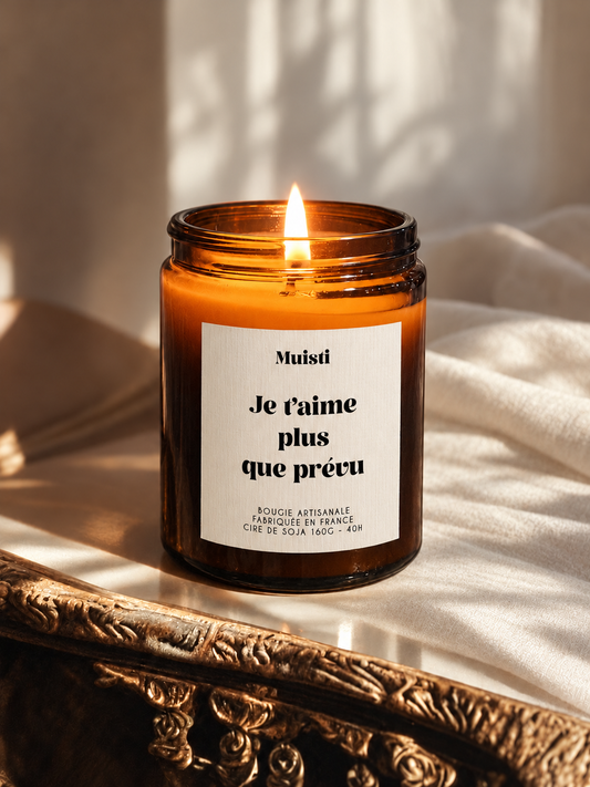 Bougie Muisti « Je t’aime plus que prévu » allumée, en pot ambré sur un miroir ancien.