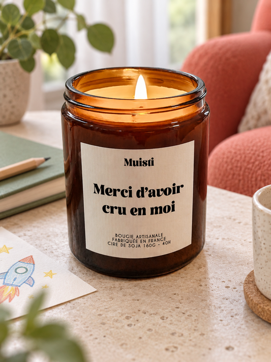 Bougie Muisti « Merci d'avoir cru en moi » 160 g allumée dans un intérieur à la lumière douce du jour.