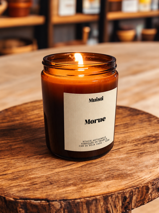 Bougie Muisti « Morue » allumée, en pot ambré dans son décor d’origine.