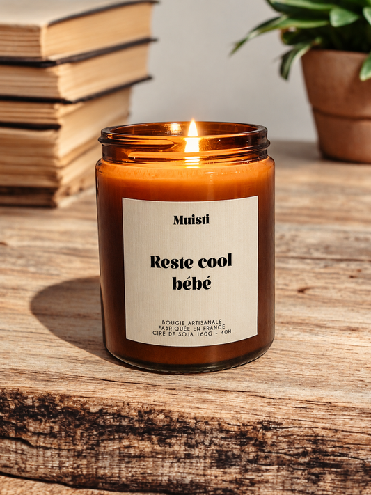 Bougie Muisti « Reste cool bébé » allumée, en pot ambré dans son décor d’origine.