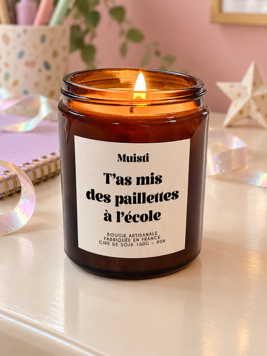 Bougie Muisti « T'as mis des paillettes à l'école » 160 g allumée dans un intérieur à la lumière douce du jour.