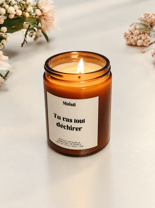 Bougie Muisti « Tu vas tout déchirer » allumée, en pot ambré dans son décor d’origine.