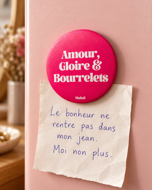 Magnet Muisti « Amour, Gloire & Bourrelets » tenant un petit mot dans une scène du quotidien.