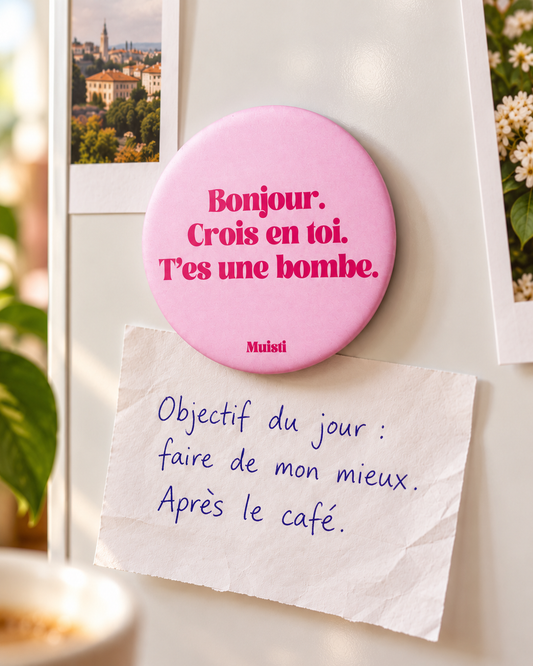 Magnet Muisti « Bonjour. Crois en toi. T’es une bombe. » tenant un petit mot dans une scène du quotidien.