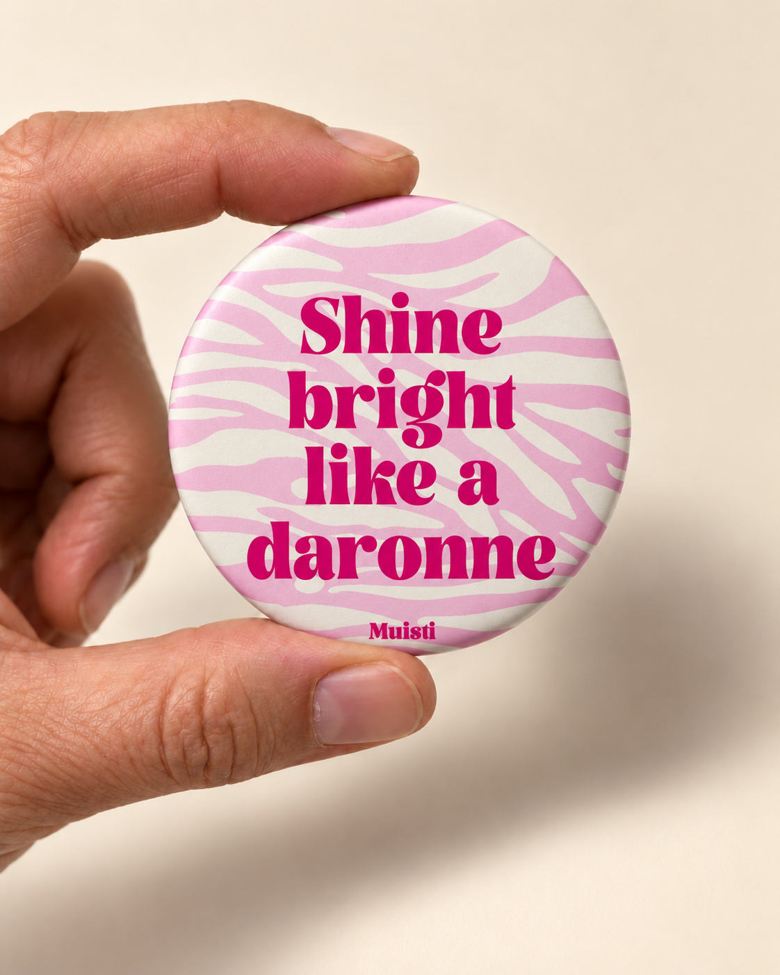 Magnet Muisti « Shine bright like a daronne » tenu entre le pouce et l’index sur fond ivoire.
