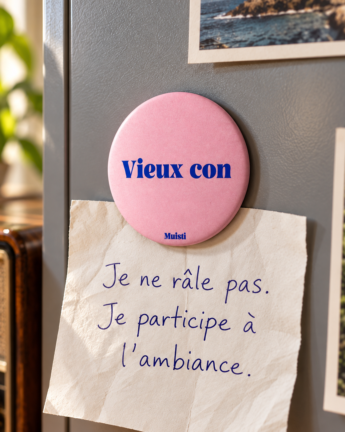 Magnet Muisti « Vieux con » tenant un petit mot sur un tableau magnétique.